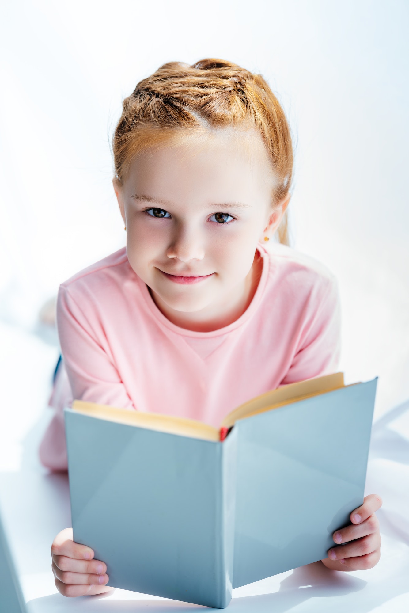 adorable child holding book and smiling at camera