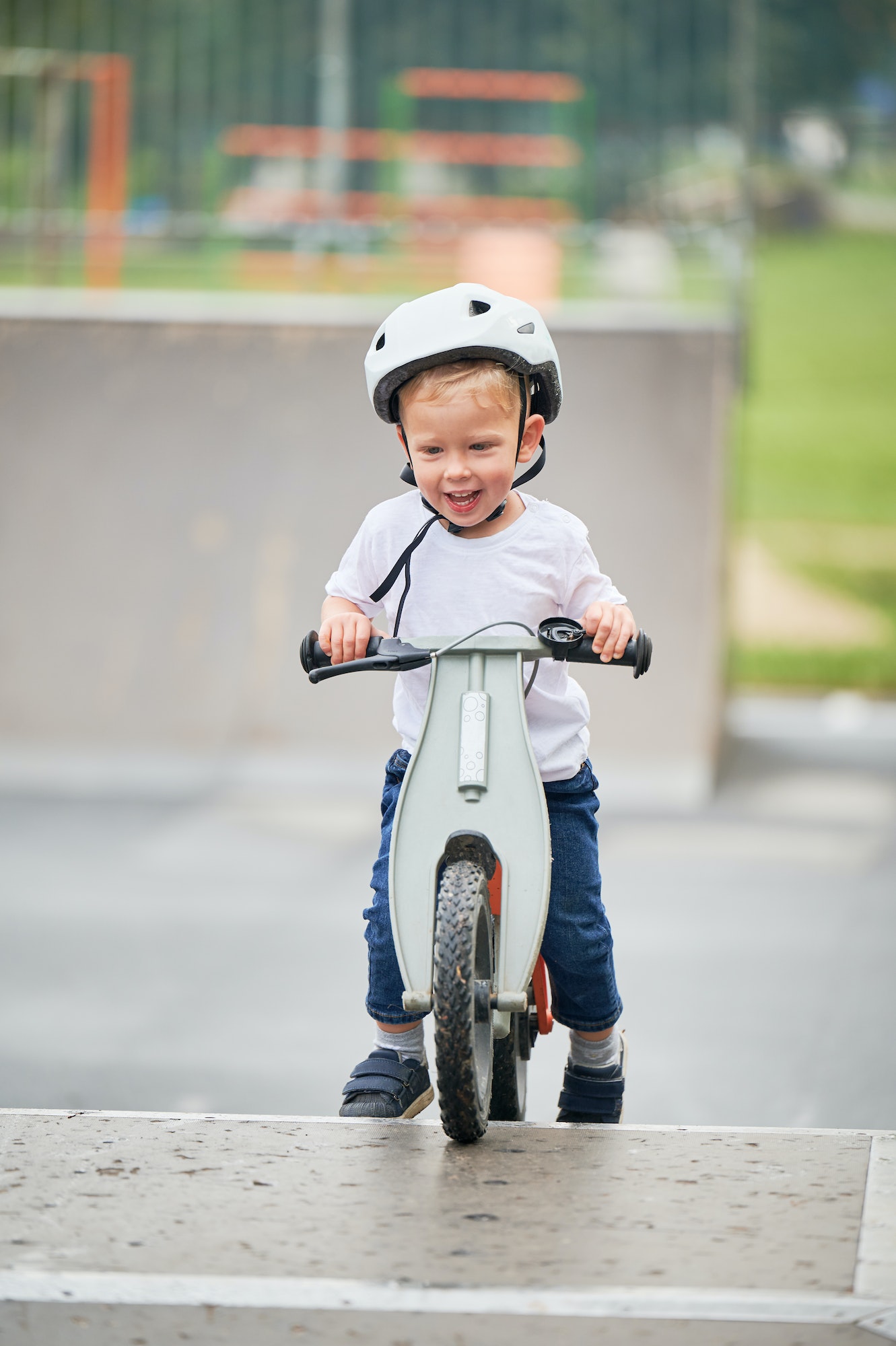Toddler kid learning to ride on run bicycle at skate park.